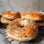 High-protein everything bagel topped with sesame and poppy seeds on a white plate